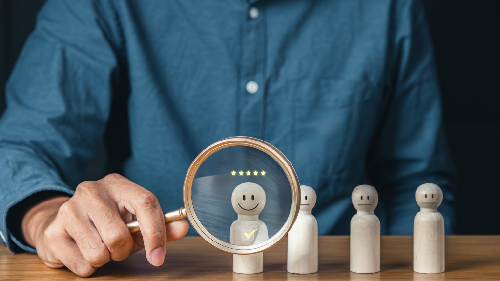 Magnifying glass highlighting a top-rated candidate during AI recruiting interview screening and bias evaluation.